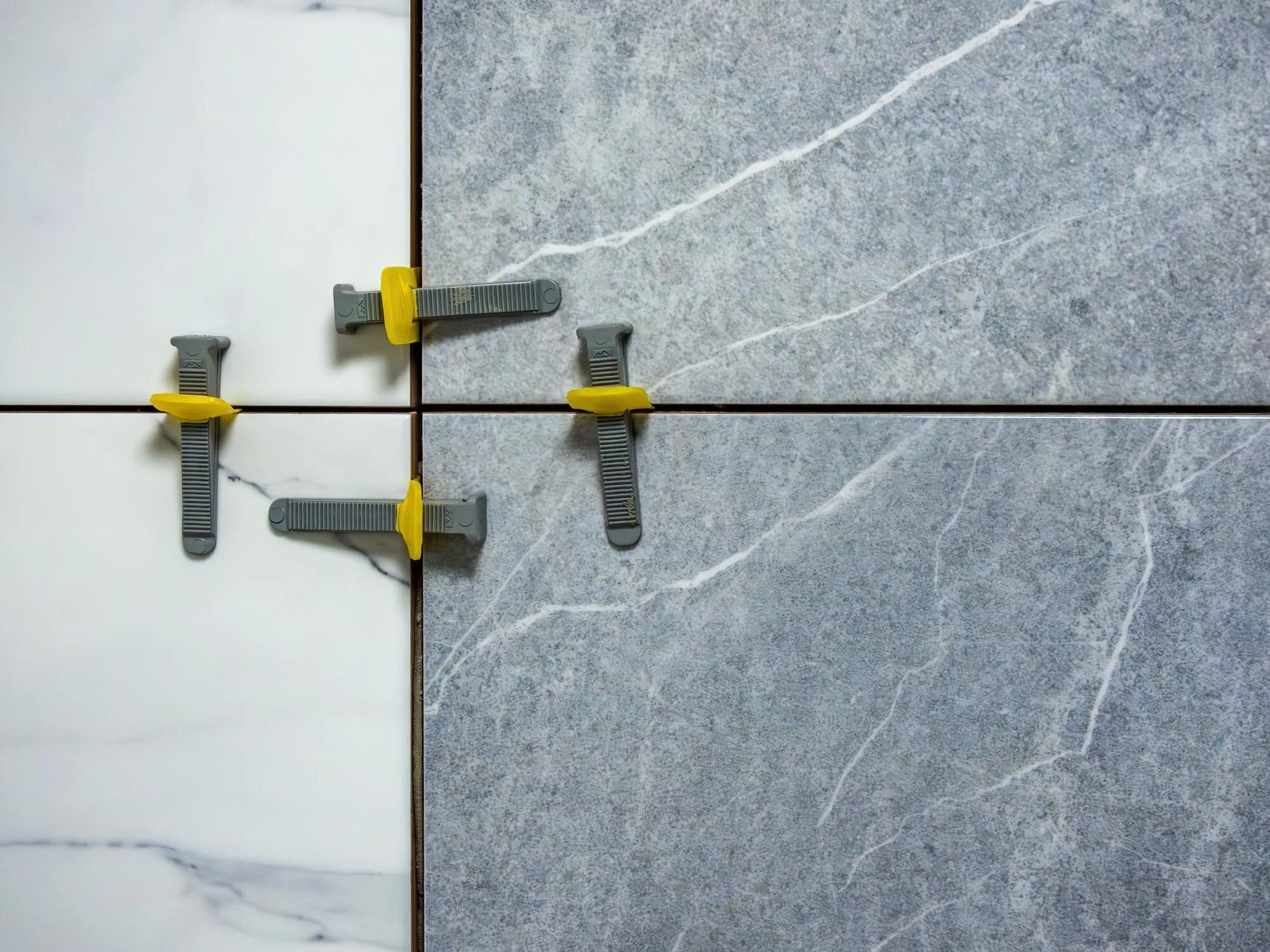Close view of porcelain wall tile held in alignment with leveling clips